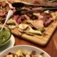 table with green sauce, and a platter with grilled fennel and steak